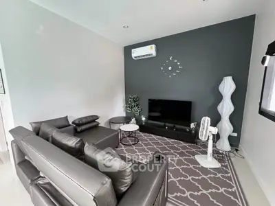 Modern living room with sleek black furniture and stylish decor, featuring a wall-mounted air conditioner and flat-screen TV.