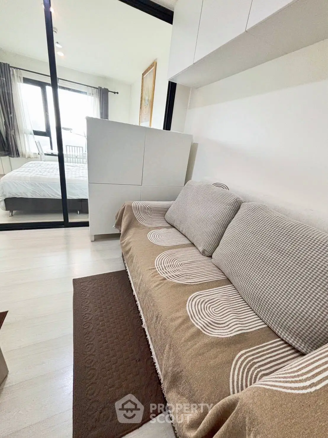 Cozy modern living room with stylish sofa and bedroom view