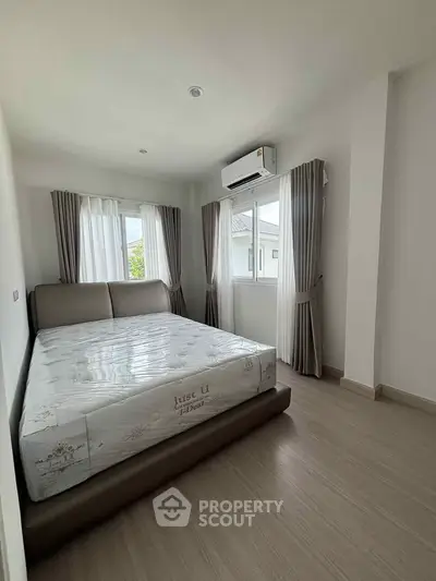 Spacious bedroom with large windows and modern decor, perfect for relaxation.
