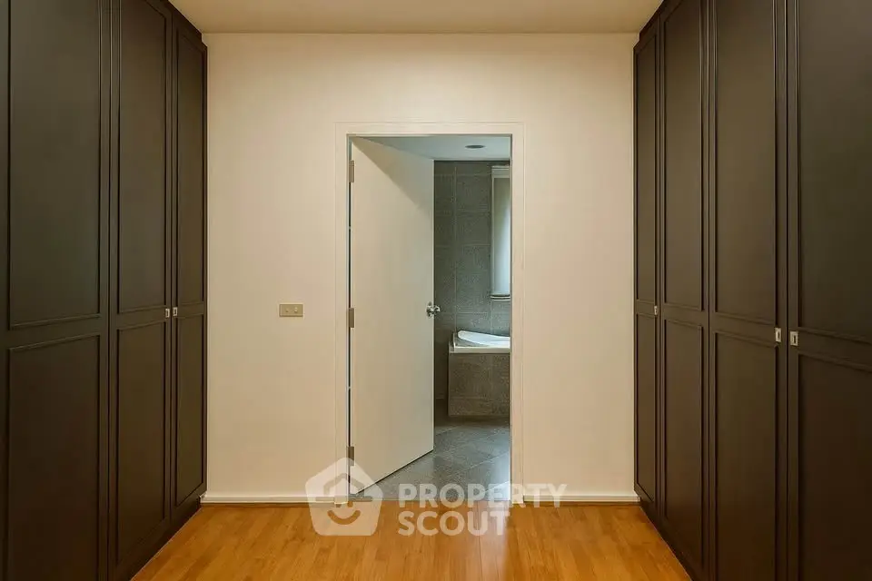 Spacious hallway with wooden flooring leading to a modern bathroom.