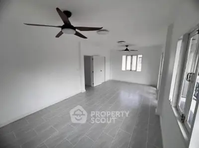 Spacious unfurnished room with modern ceiling fans and large windows for natural light.