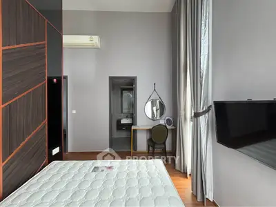 Modern bedroom with high ceiling, wall-mounted TV, and stylish decor in a contemporary apartment.