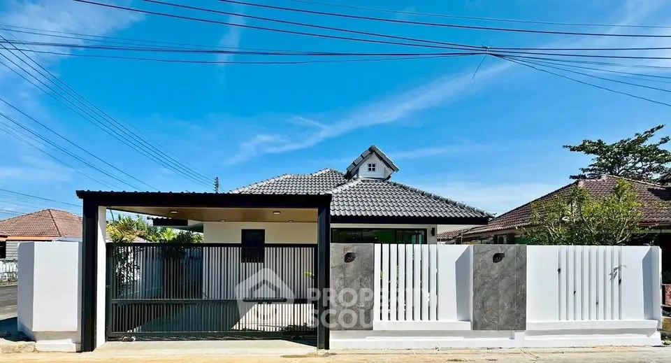 Charming single-story home with modern fence and carport under clear blue sky.