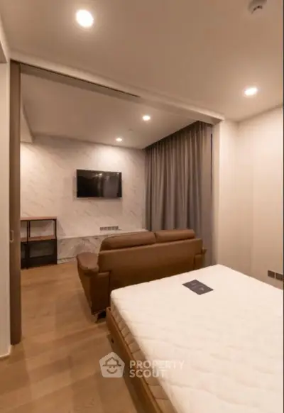 Modern bedroom with cozy seating area and wall-mounted TV, perfect for relaxation.