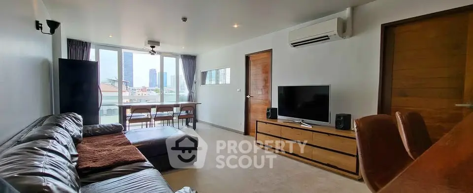 Spacious modern living room with leather sofa and city view, perfect for urban living.