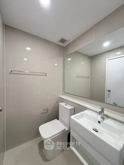Modern bathroom with sleek fixtures and large mirror in a contemporary apartment.