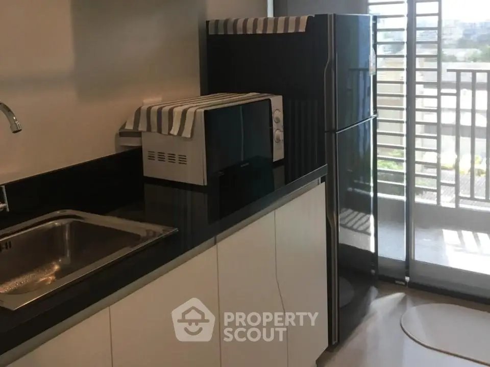 Modern kitchen with sleek countertops and appliances, featuring a large window with balcony view.