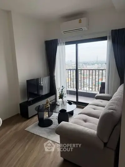 Modern living room with city view, featuring cozy sofa, sleek TV setup, and large windows leading to balcony.