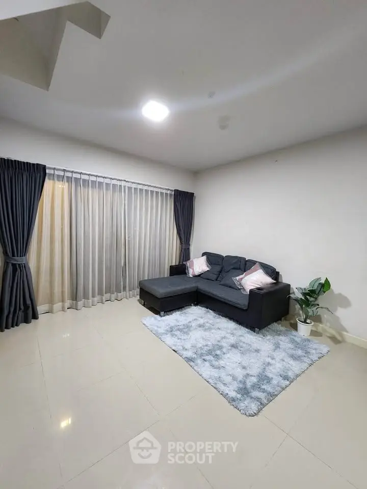 Spacious living room with modern sofa and large window, perfect for relaxation.