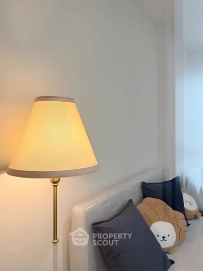 Cozy bedroom corner with stylish lamp and plush pillows, perfect for relaxation.