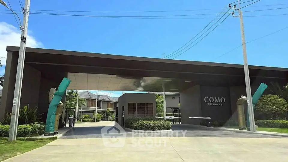 Modern entrance of COMO residential complex with lush greenery and clear blue sky.