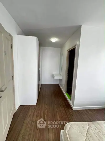 Spacious bedroom with wooden flooring and minimalist design, featuring a built-in wardrobe and modern lighting.