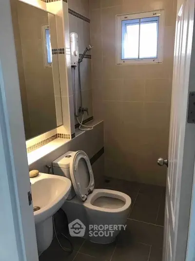 Compact modern bathroom with shower and toilet in neutral tones