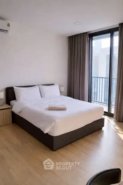 Modern bedroom with large window and balcony access in urban apartment