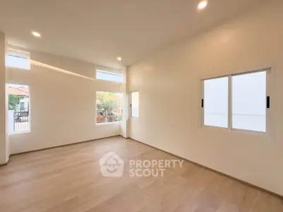 Spacious empty room with large windows and wooden flooring, perfect for customization.