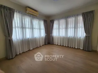 Spacious empty room with large windows and elegant curtains, perfect for customization.