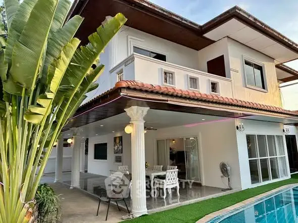 Stunning two-story home with poolside patio and lush greenery, perfect for luxurious living.