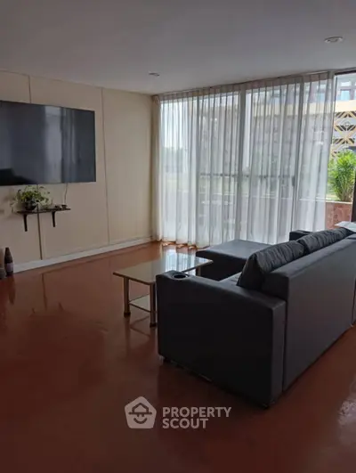 Spacious living room with large window and modern furniture, perfect for relaxation and entertainment.