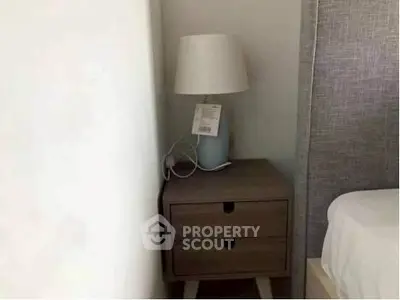 Cozy bedroom corner with modern nightstand and stylish lamp.