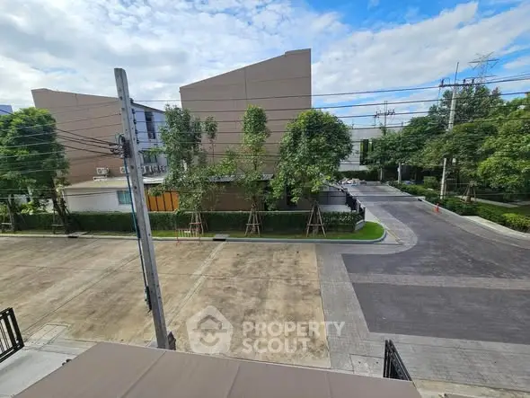 Modern residential street view with lush greenery and clear blue sky.