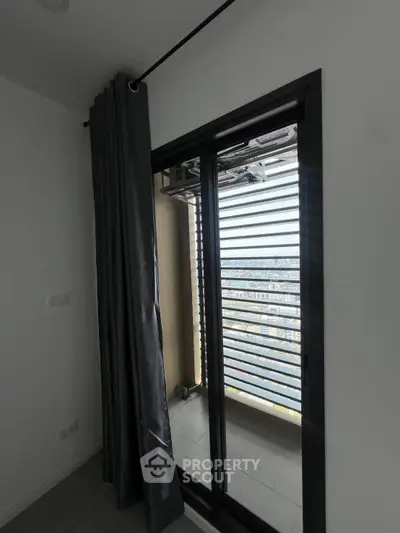 Modern apartment balcony with city view and sleek sliding doors.