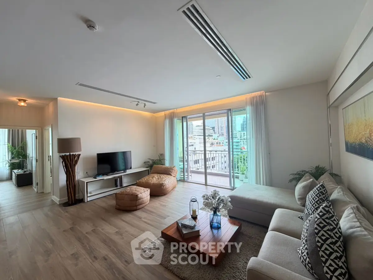 Spacious modern living room with large windows and city view, featuring stylish decor and comfortable seating.