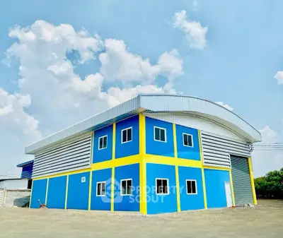 Modern industrial warehouse with vibrant blue and yellow exterior under a clear sky.