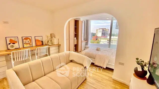 Chic open-plan living room with cozy sofa and stylish decor, featuring a bright bedroom view.