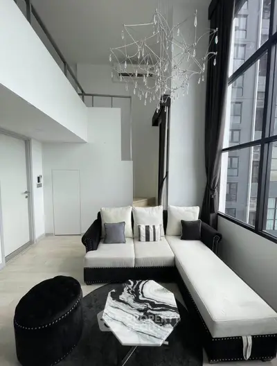 Luxurious modern living room with high ceilings, elegant chandelier, and stylish furniture in a loft apartment.