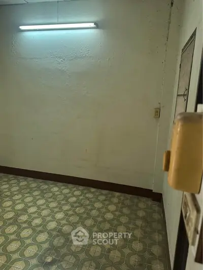 Spacious room with vintage patterned flooring and fluorescent lighting, ideal for creative renovation.