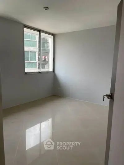 Spacious empty room with large window and tiled floor, perfect for customization.