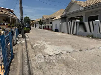 Charming suburban street with modern houses and well-maintained exteriors under a clear blue sky.