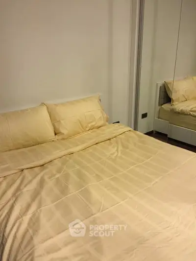 Cozy bedroom with mirrored wardrobe and soft lighting, perfect for relaxation.