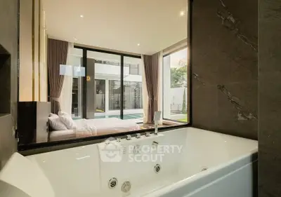 Luxurious bedroom with ensuite jacuzzi overlooking a modern pool and garden view.