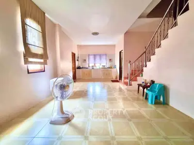 Spacious living room with open layout and natural light, featuring a fan and staircase.