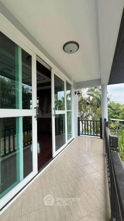 Charming balcony with lush garden view and elegant sliding glass doors.