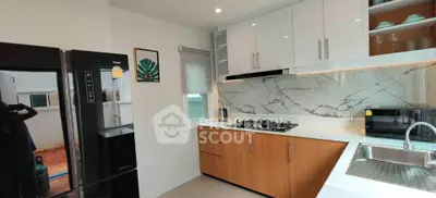 Modern kitchen with sleek cabinetry, marble backsplash, and stainless steel appliances.