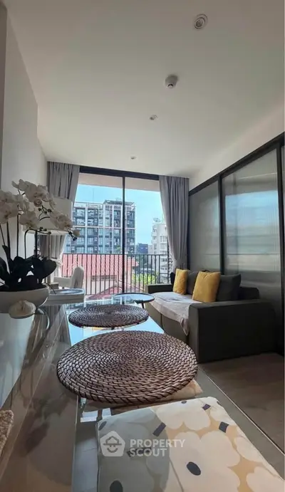 Modern living room with large windows and city view, featuring stylish decor and cozy seating area.