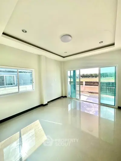 Bright living room with large windows and balcony access, offering ample natural light and modern design.