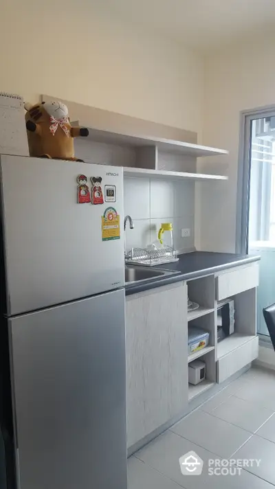 Modern kitchen with sleek cabinetry and stainless steel fridge in a cozy apartment