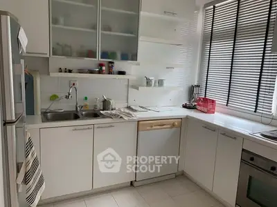 Modern kitchen with sleek cabinetry and natural light, featuring a dishwasher and oven.