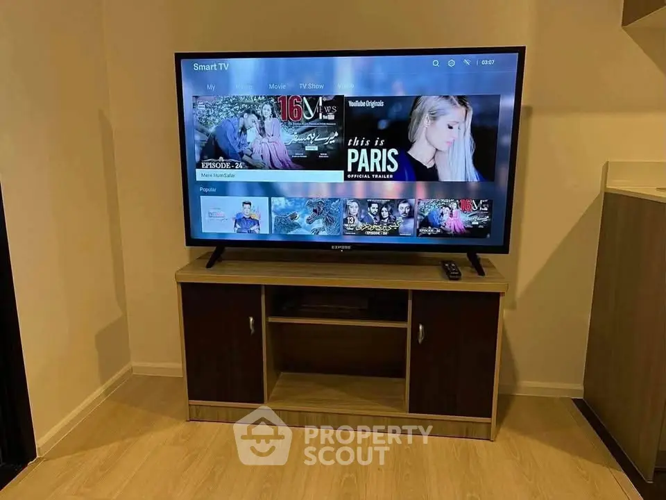 Modern living room with smart TV and stylish wooden TV stand, perfect for entertainment.