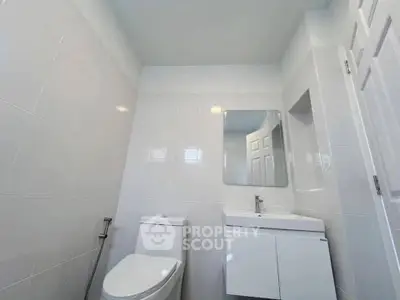 Modern bathroom with sleek white tiles and contemporary fixtures.