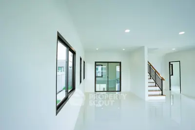 Spacious modern living room with large windows and sleek staircase in a bright home.