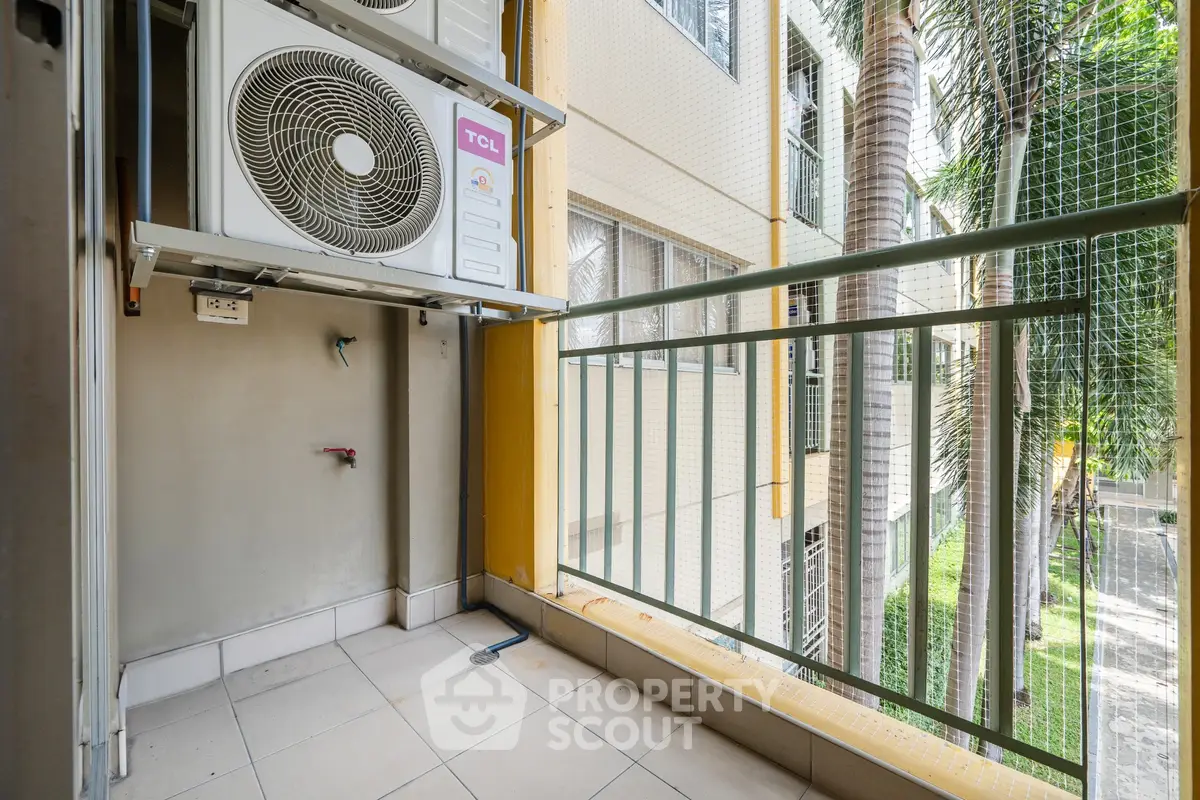Compact balcony with air conditioning unit and view of palm trees