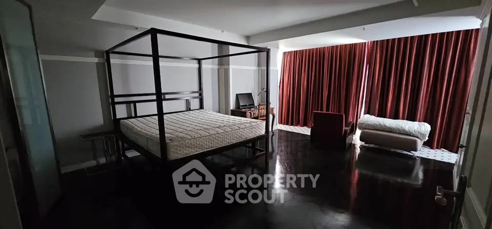 Spacious bedroom with elegant four-poster bed and luxurious dark flooring.