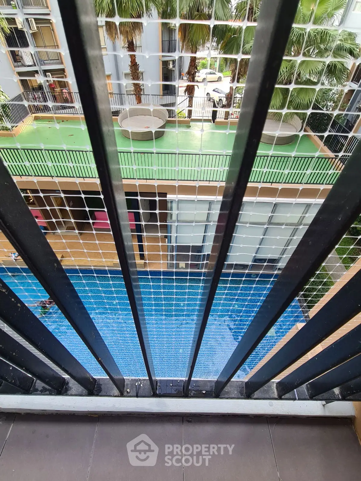 Modern apartment balcony with pool and garden view, ideal for urban living.