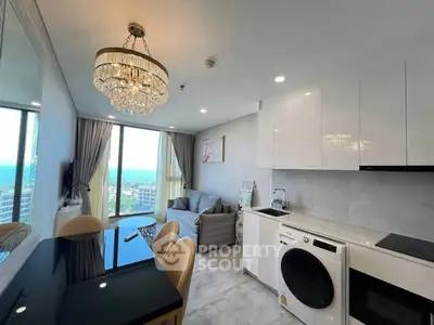 Luxurious modern living room with ocean view, elegant chandelier, and sleek kitchen appliances.