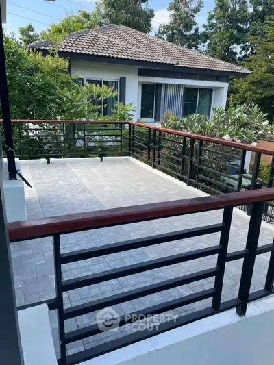 Spacious balcony with modern railing and lush greenery view, perfect for outdoor relaxation and entertainment.