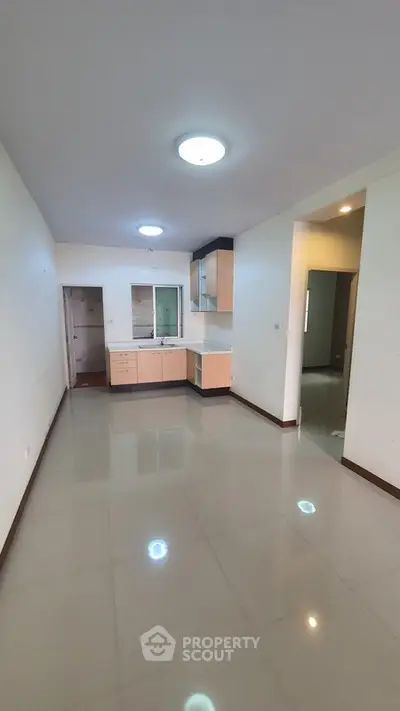 Spacious open-layout kitchen in modern apartment with sleek cabinetry and ample natural light.